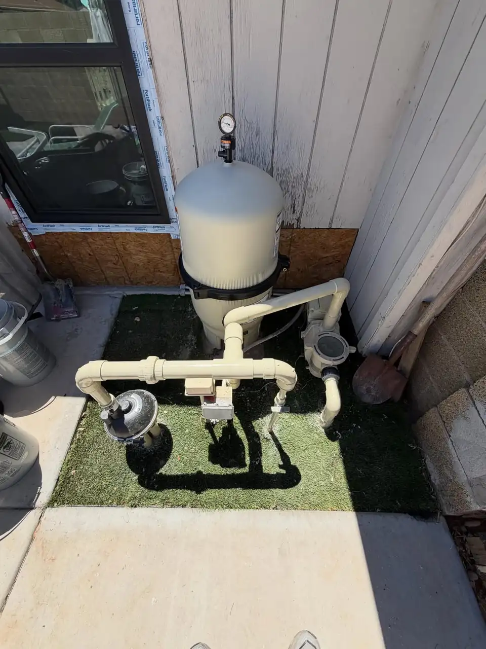 A DE filter and pump plumbing on a pool equipment pad