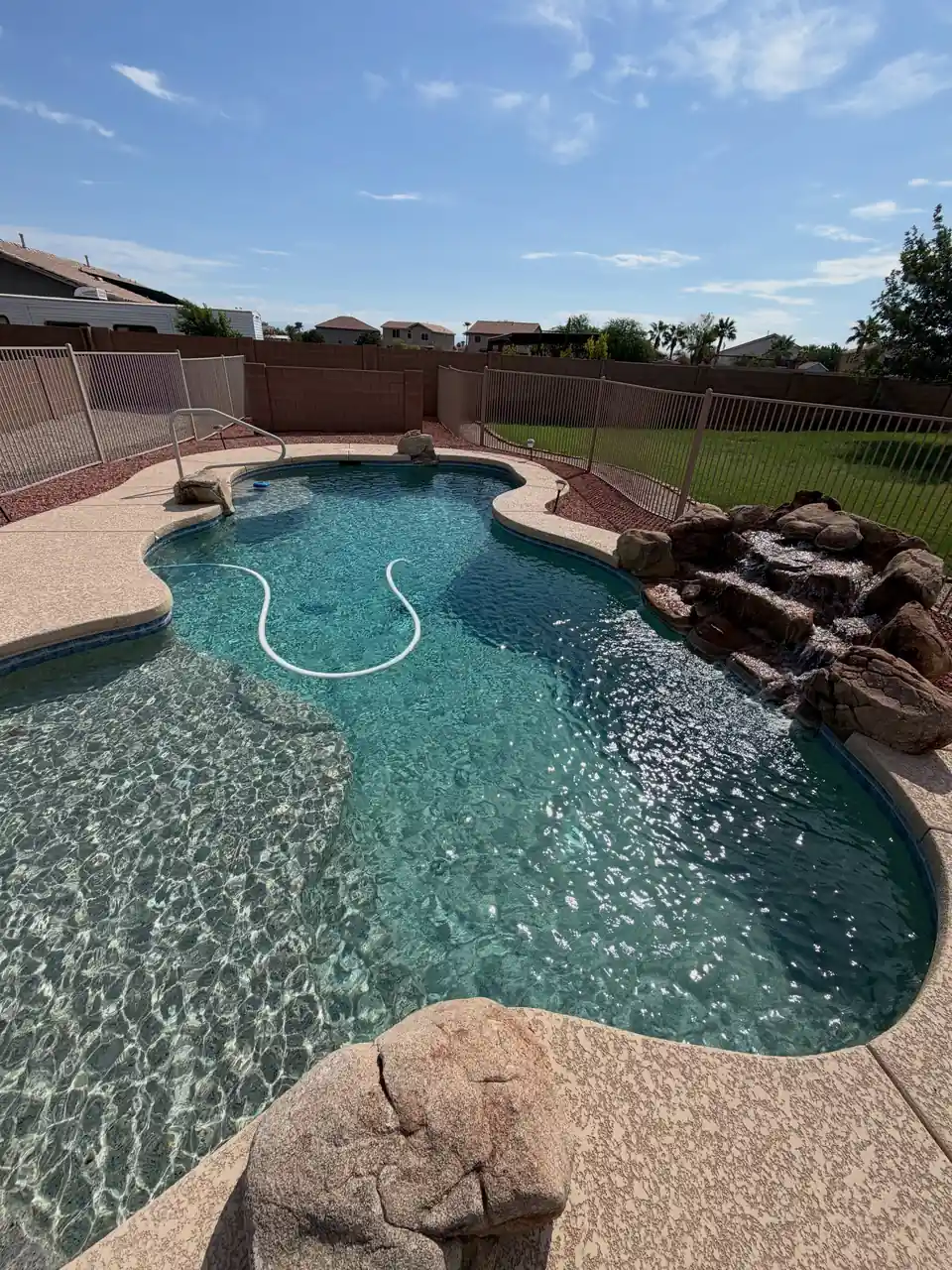 A freeform pool with a rock waterfall and clear water